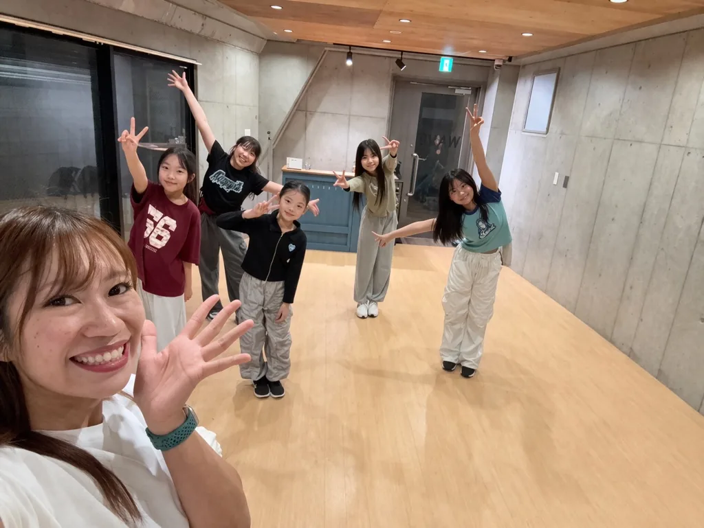 スタジオで笑顔でポーズをとる講師と子どもたち